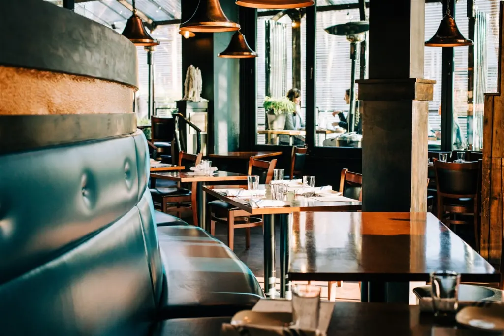 Grappa's dining room in Queen Anne with a teal leather banquette, set tables and copper pendant lights, before MISSIO at The Funhouse