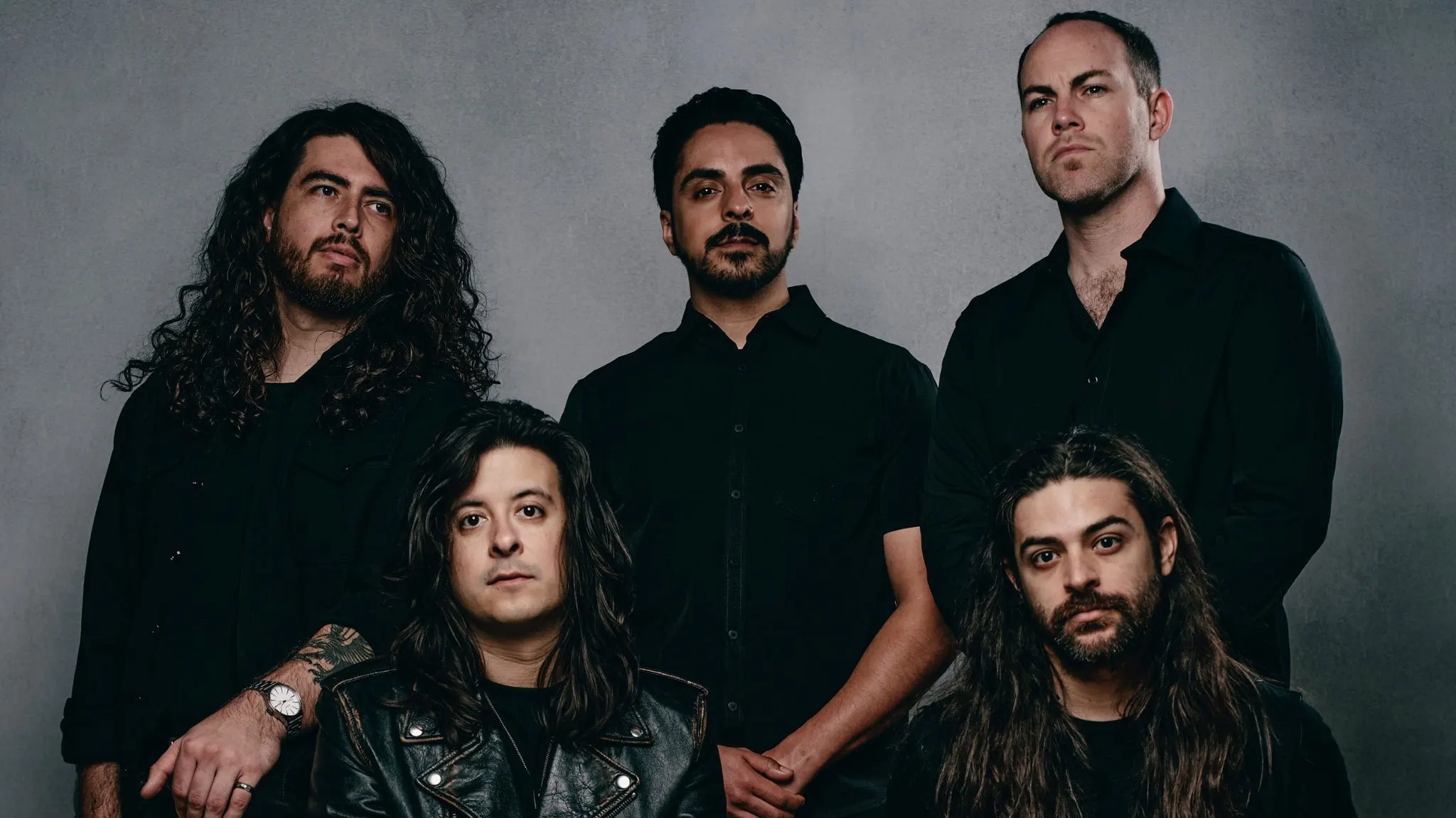 The five members of Hail The Sun in black shirts posing against a grey studio backdrop, ahead of their El Corazon show with A Lot Like Birds near Grappa
